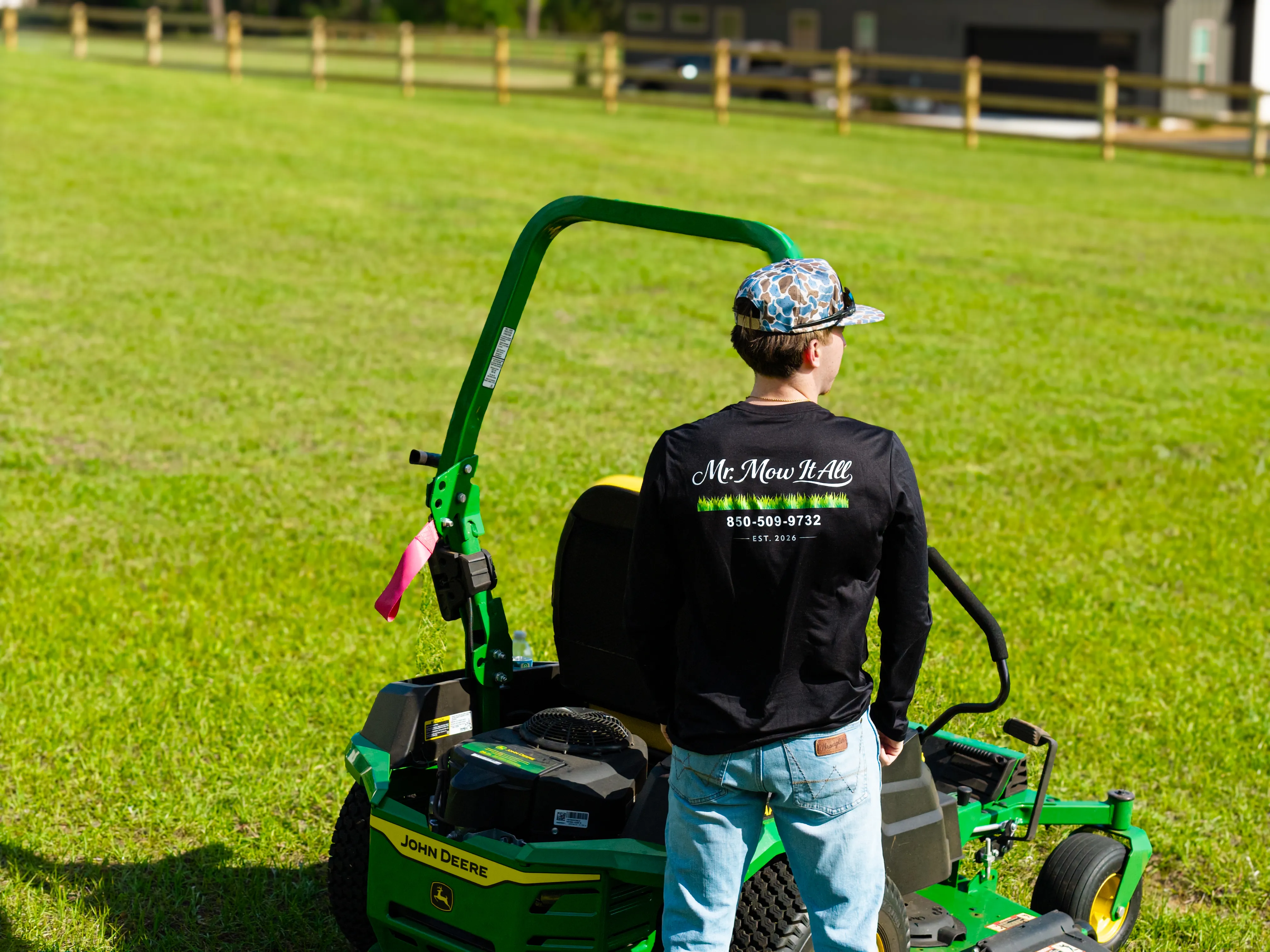 Mr. MowItAll owner in branded gear beside his green John Deere mower