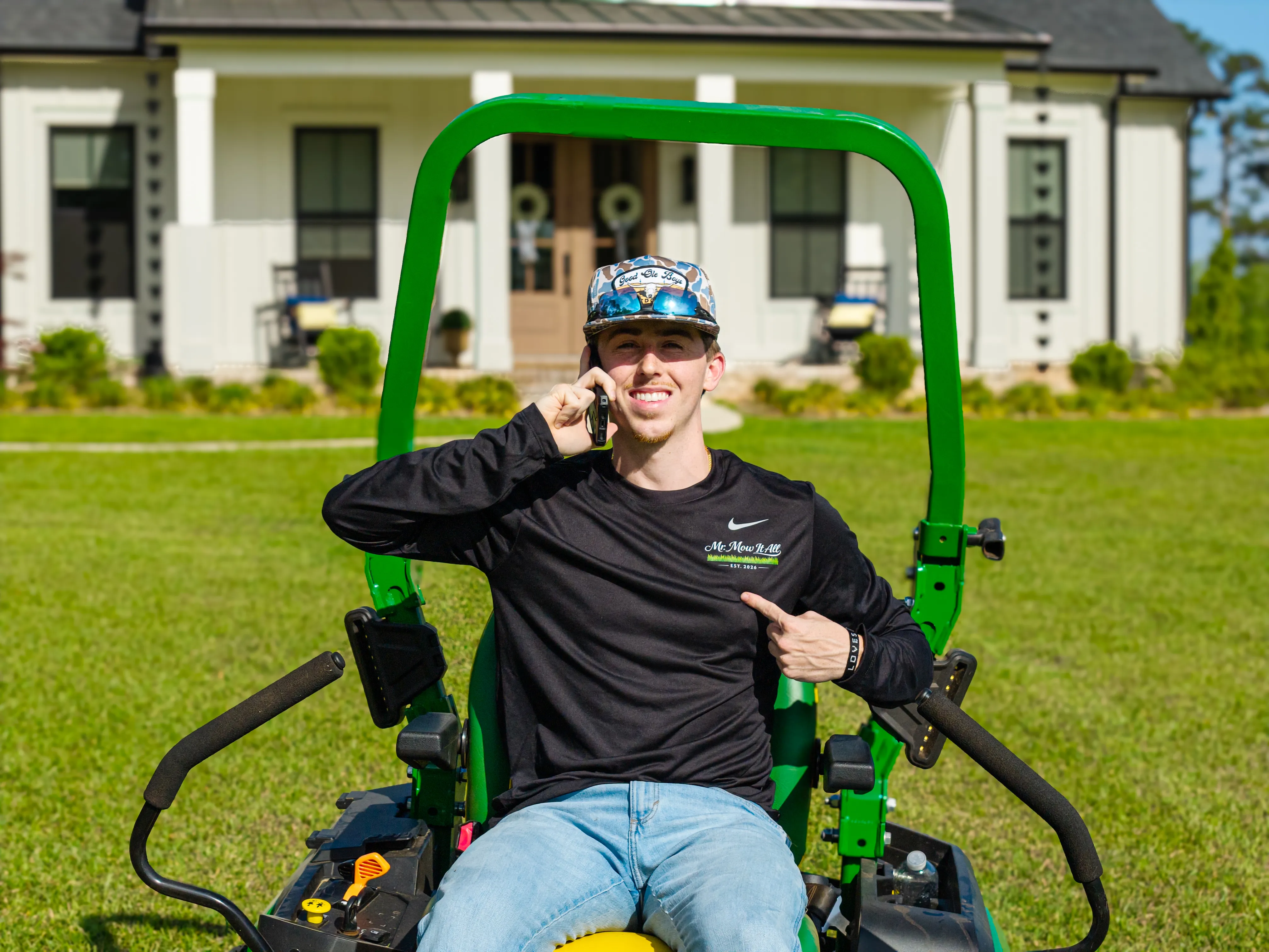 Mr. MowItAll owner taking a call from a mower in front of a customer's home