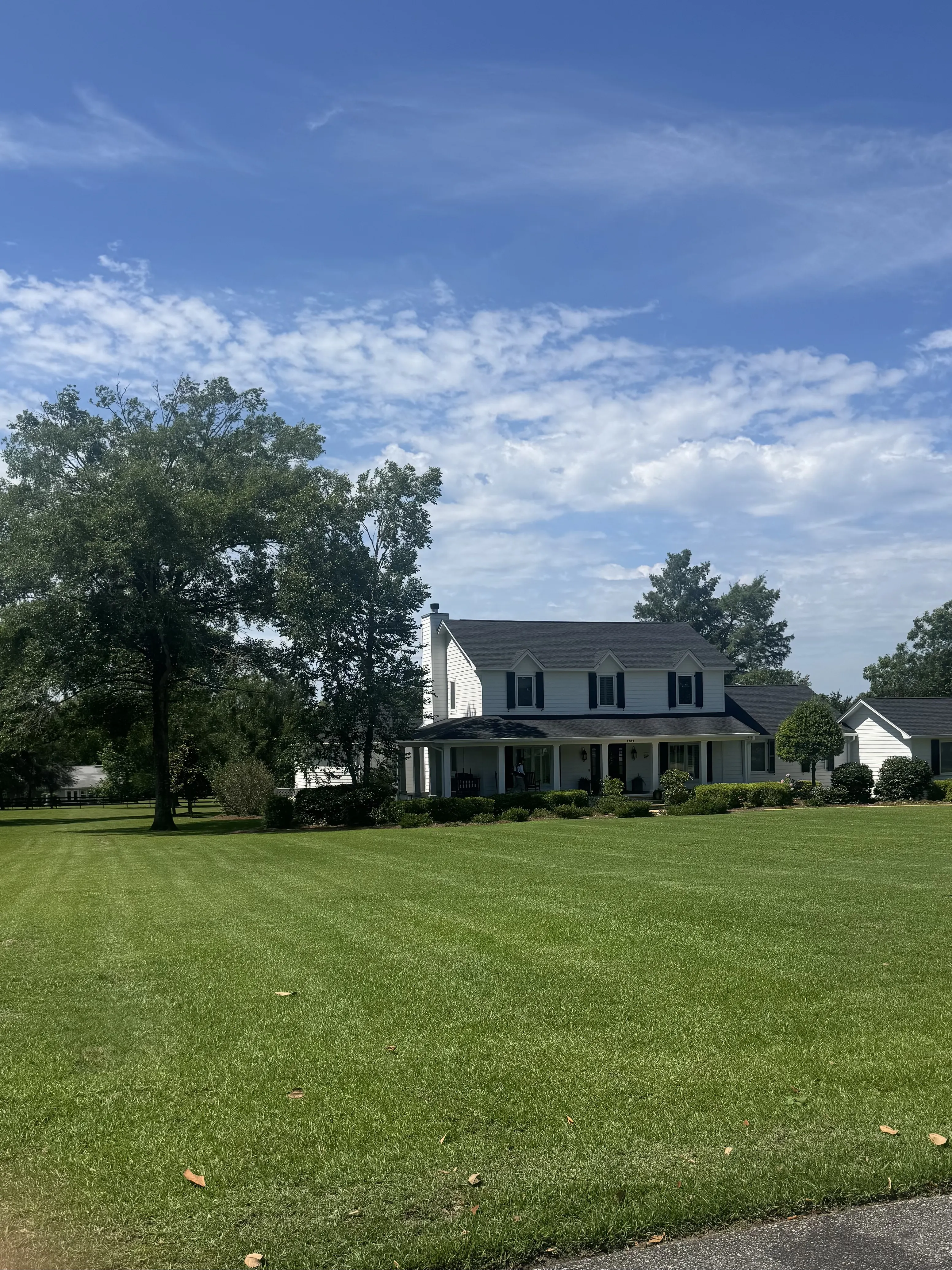 Freshly mowed and striped front lawn at a two-story Tallahassee farmhouse