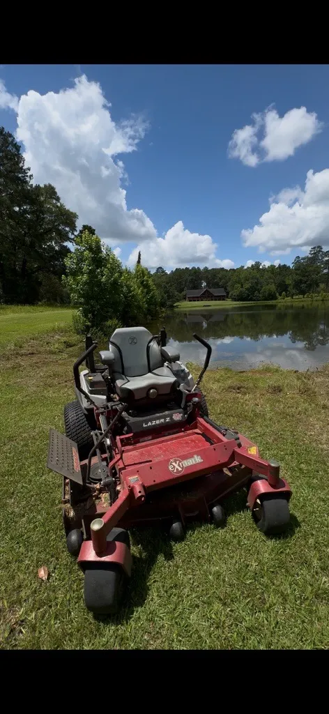 Mr. MowItAll Exmark Lazer Z commercial zero-turn mower parked beside a pond