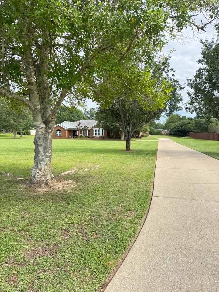 Brick ranch home with a freshly mowed lawn viewed along a curving driveway