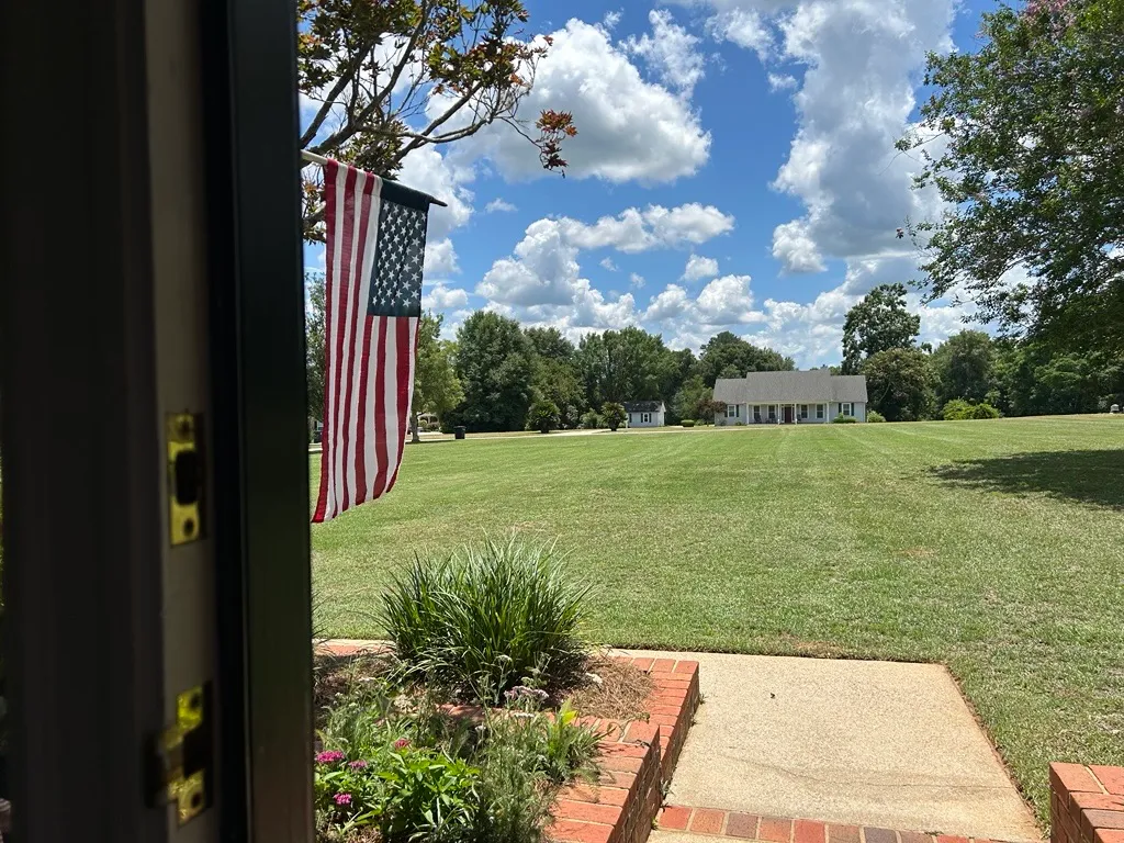 American flag and brick walkway framing a freshly striped front lawn in Leon County