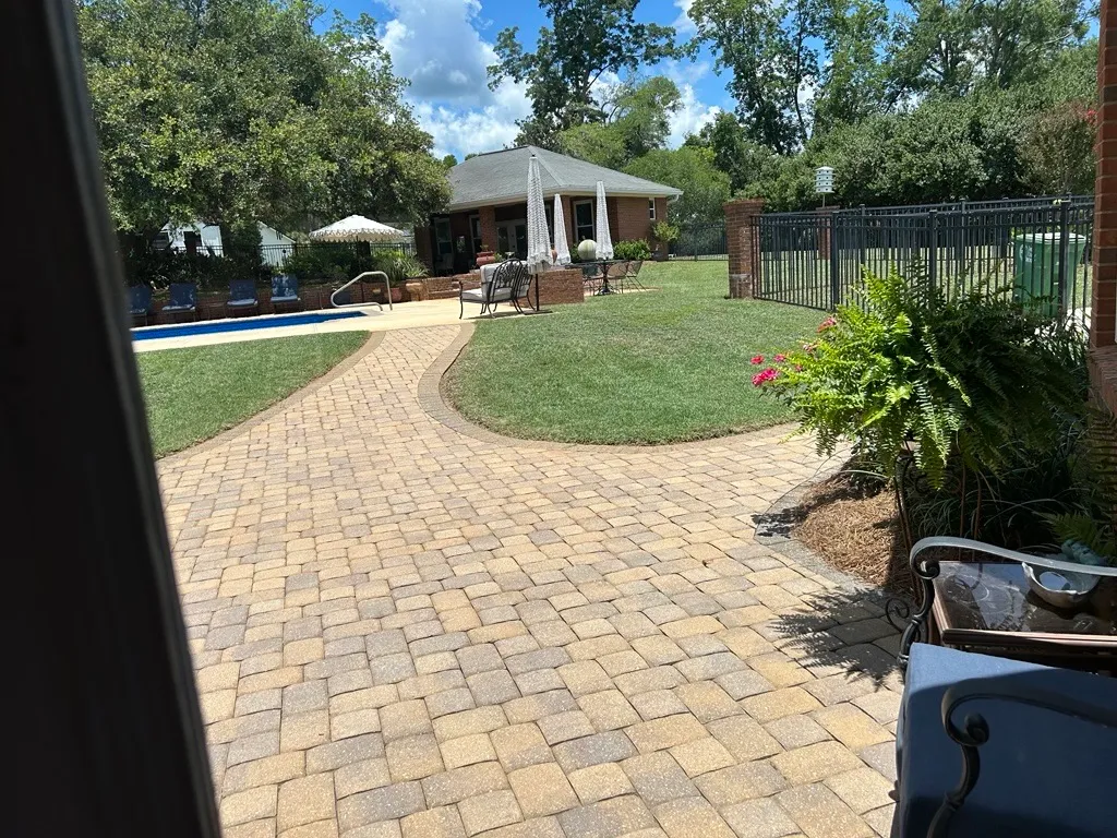 Backyard paver patio, pool, and manicured lawn at an upscale Tallahassee home