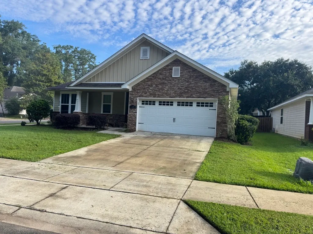 Freshly cut green lawn in front of a stone-and-siding craftsman home