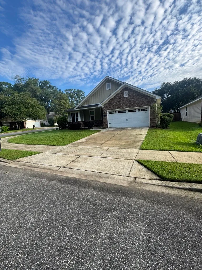 Neatly mowed lawn and edged driveway at a craftsman home under a mackerel sky