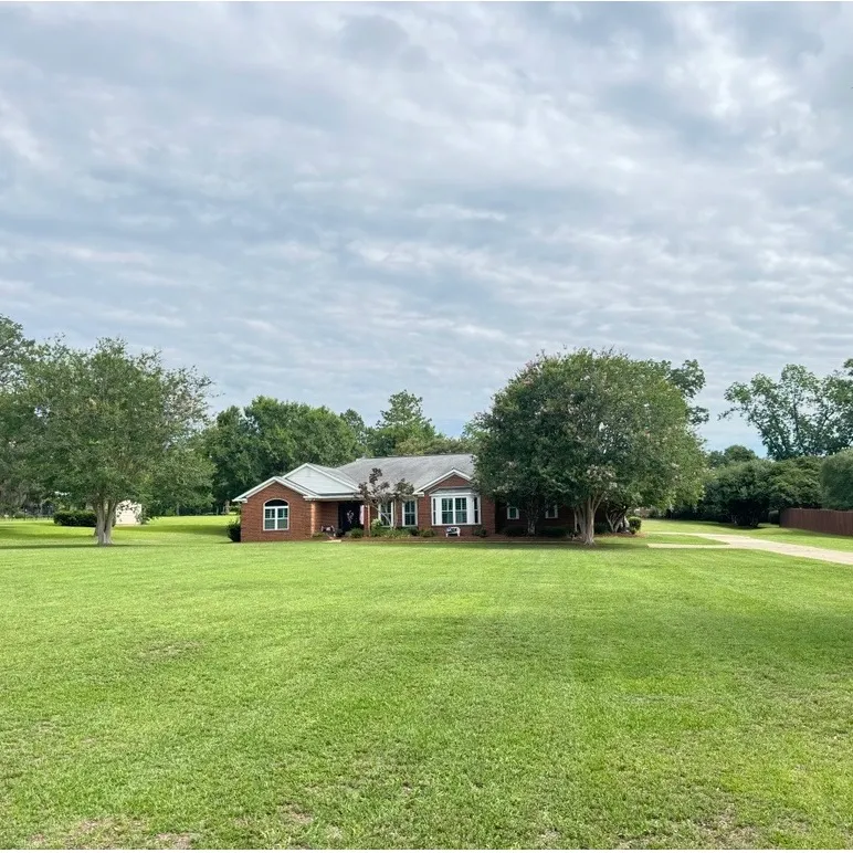 The same brick ranch home with a freshly mowed, tidy front lawn after Mr. MowItAll service